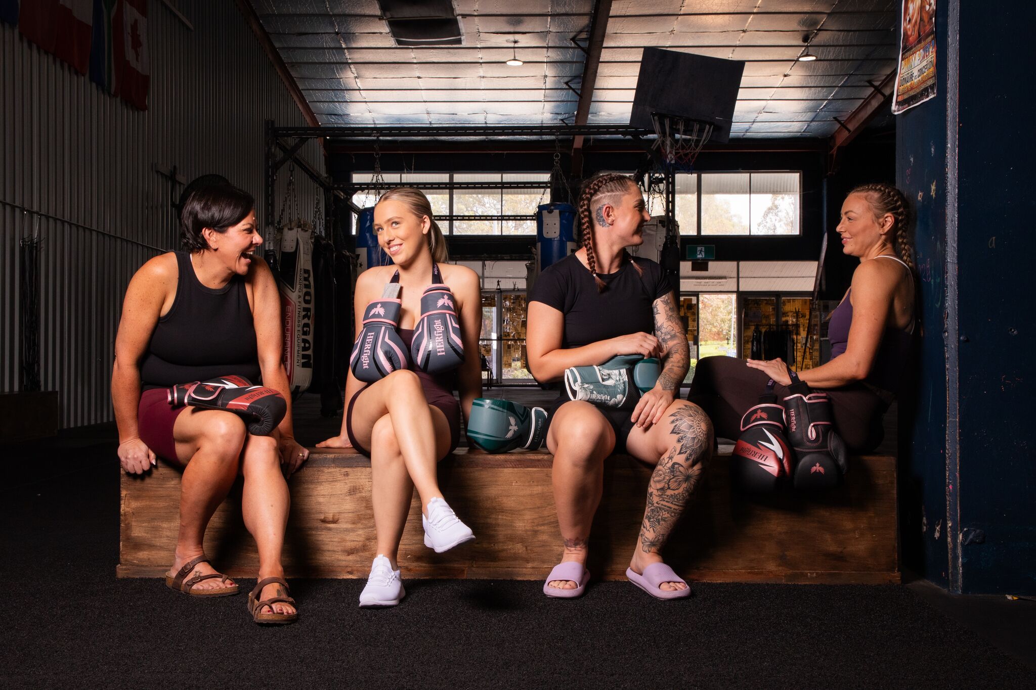 Women’s boxing gloves for women, post-training in a gym, holding gloves on a bench